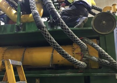 Mid-process of over 6, 2-inch multi-spiral hose with whip socks and spiral guard for safety on an aggressive manufacturing machine. For a large hay exporting company.